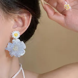 Primer plano macro de pendientes de flores de cristal azul translúcido con una margarita