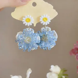 Detalle de elegantes pendientes de flores de cuentas azules con acentos de margaritas