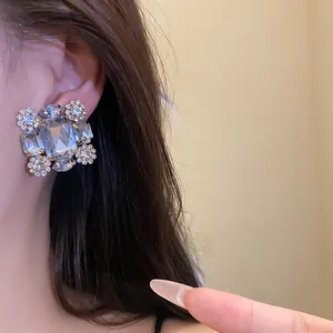 Exquisite Nahaufnahme von luxuriösen funkelnden quadratischen Strass-Ohrclips an einem Ohr