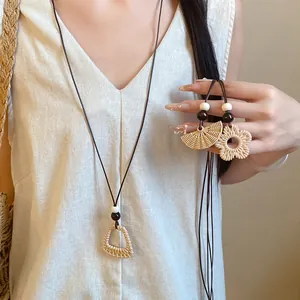 Close-up of ethnic geometric straw woven pendants with wooden beads and wax cord.