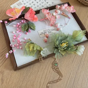 Detailed view of pink lily of the valley hair clips with tassels and green floral accents.