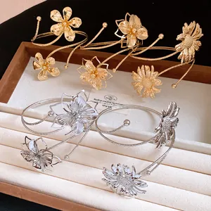 Detailed shot of pleated flower arm cuffs in gold and silver finishes on a tray