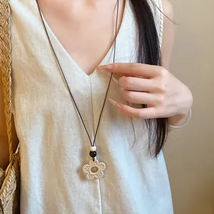 Close-up detail of a boho wax cord necklace with a resin flower pendant on a model