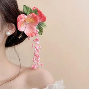 Close-up detail of a pink lily-of-the-valley tassel hair clip styled on a model's hair