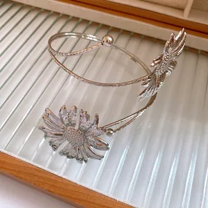Detailed close-up of a silver metal flower arm cuff with textured sunflower charms for women
