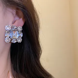 Nahaufnahme eines luxuriösen quadratischen Kristallohrrings am Ohr mit dunklem Haar