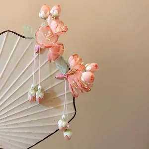 Detailed view of handmade pink lily-of-the-valley hair clip with elegant silk tassels