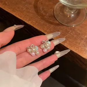 Elegant bow knot pearl stud earrings with zircon details shown in hand close-up