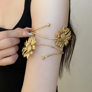 Close-up of gold metal arm cuff featuring textured sunflower designs on arm.