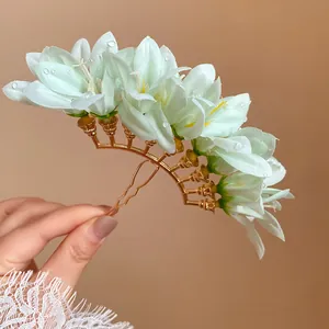 Close-up of elegant mint green fabric flower hair fork with dew drops and gold base