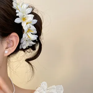 Detailed view of white floral hair accessories and pearl earrings on a model