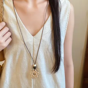 Close-up view of an ethnic resin flower pendant necklace with wax cord on a model.