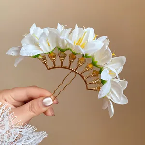 Detailed view of the white fabric flowers and golden U-shaped pin of the hair accessory.