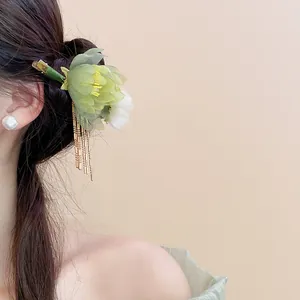 Macro view of elegant Chinese style green lotus floral hair clip with gold tassels