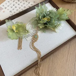 Detailed view of green fabric flowers with elegant gold beaded tassels on Hanfu hair clips
