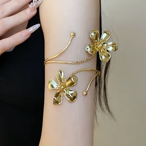 Detail of a gold metal arm cuff featuring unique crumpled flower design on model's arm.