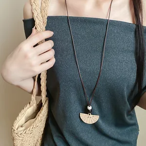 Close-up detail of ethnic resin fan pendant necklace with wax cord and wooden beads