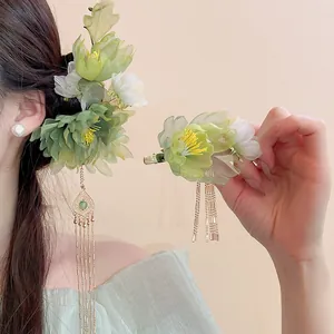 Detailed close-up of green flower hair clips with elegant gold tassels for Hanfu styling