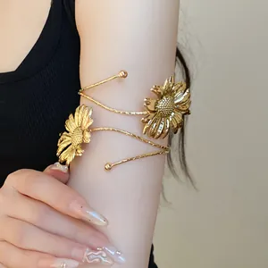 Elegant gold arm cuff with intricate pleated sunflower floral design on a female arm