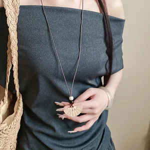 Close-up of woven fan pendant necklace with brown wax rope and wooden beads