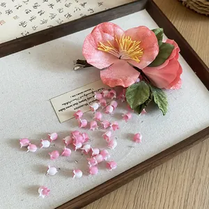 Detailed view of handmade pink camellia hair clip with lily of the valley tassel beads