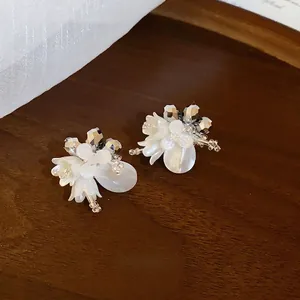 Elegante weiße Blumen-Perlenohrstecker im französischen Stil auf einem Holztablett