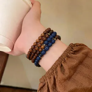 Close-up of retro layered bracelets with brown wood and blue stone beads on wrist.