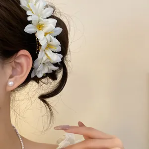 Detailed view of an elegant white floral hair accessory worn in a stylish hair bun