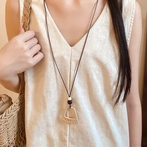 Close-up of a bohemian style woven geometric pendant necklace worn on a linen dress