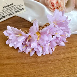 Detailed view of the pink fabric flower hair pin with dewdrop accents on a wooden surface.