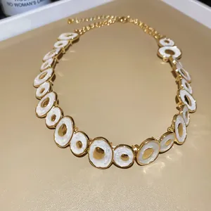 Detailed view of the vintage gold necklace with white enamel irregular round links.