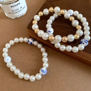 Detailed macro view of vintage ceramic and pearl beaded bracelets with blue patterns.