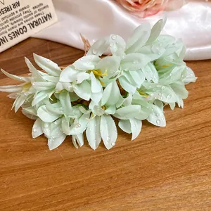 Close-up of mint green fabric flower hairpin with realistic dewdrop details on petals.