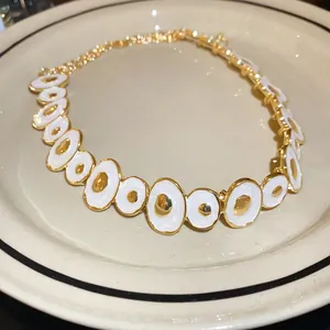 Detail view of vintage enamel irregular circle necklace with gold and white finish