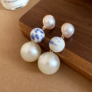 Close-up of vintage ceramic and pearl dangle earrings with blue floral patterns