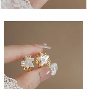 Detailed macro view of pink mother-of-pearl star earrings with gold accents.