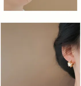 Close-up of pink star pearl earrings worn on ear, showing delicate gold metal details.