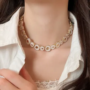 Close-up of a vintage gold-toned choker with irregular white oil-drop circular charms.