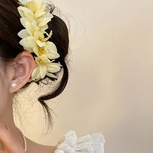 Side view detail of pale yellow floral hair accessory worn in an elegant updo hairstyle