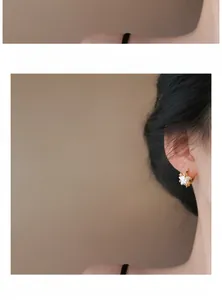 Close-up detail of stylish star-shaped pearl earrings worn on ear with a golden finish