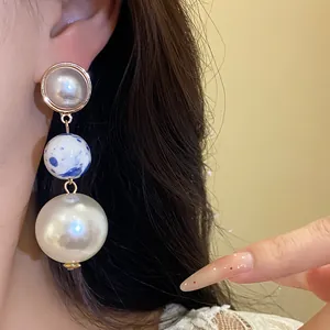 Detail view of vintage triple-ball drop earrings with blue ceramic and large white pearl