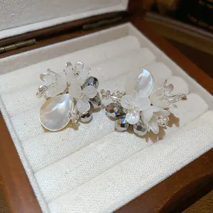 Detailansicht eleganter weißer Blumenohrringe mit Muschelpetalen in einer Schmuckschatulle