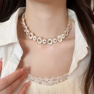 Detail view of a vintage-style irregular round enamel necklace with gold-toned metal accents.