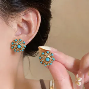 Close-up of vintage hollow flower stud earrings with gold plating and turquoise beads.