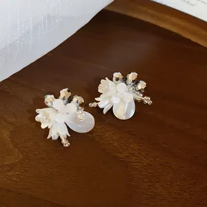 Nahaufnahme von 14k vergoldeten weißen Blumenohrsteckern mit funkelnden Perlenakzenten