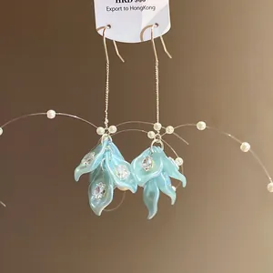 Detailed close-up of light blue petal earrings with shimmering zircon and pearls