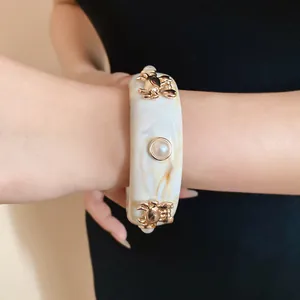 Detail of retro resin bangle featuring gold crab charms and central pearl embellishment