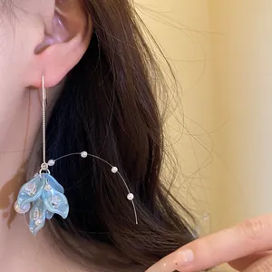 Close-up detail showing blue petal tassel earrings with pearls and zircons worn on an ear