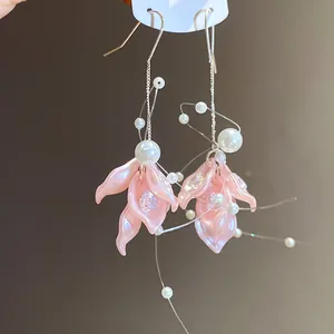 Detail view of sweet pink flower petal earrings with hanging pearls and zircons.