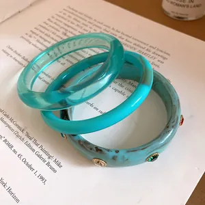 Stack of retro resin bangles with teal and marbled gemstone-encrusted designs.